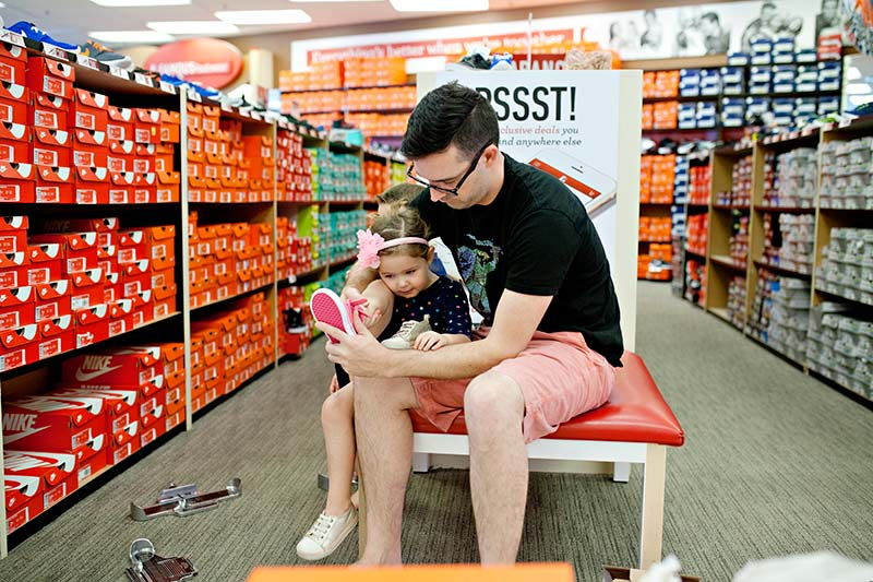Dad at store trying shoe on daughter