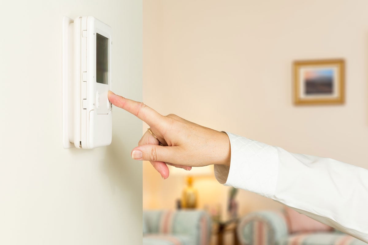 person adjusting thermostat on wall