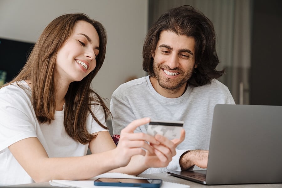 A young couple use their credit card to make a purchase online