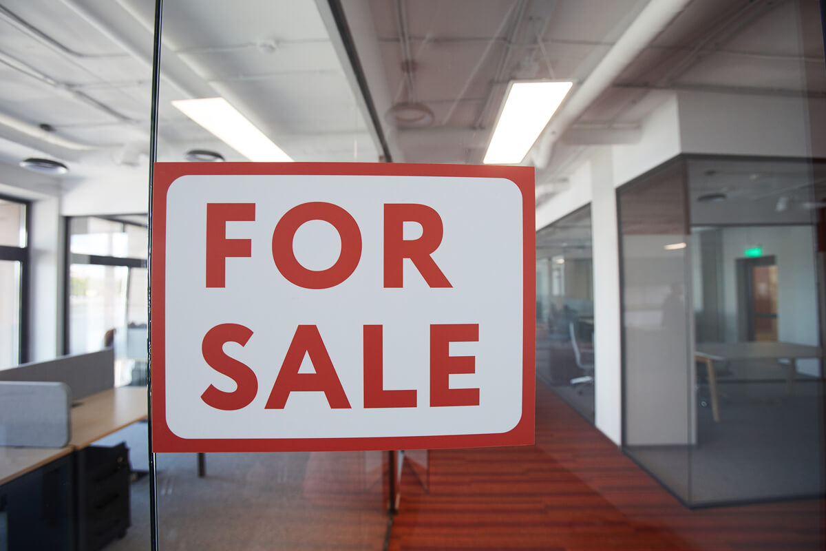 a for sale sign in the window of a contemporary office building