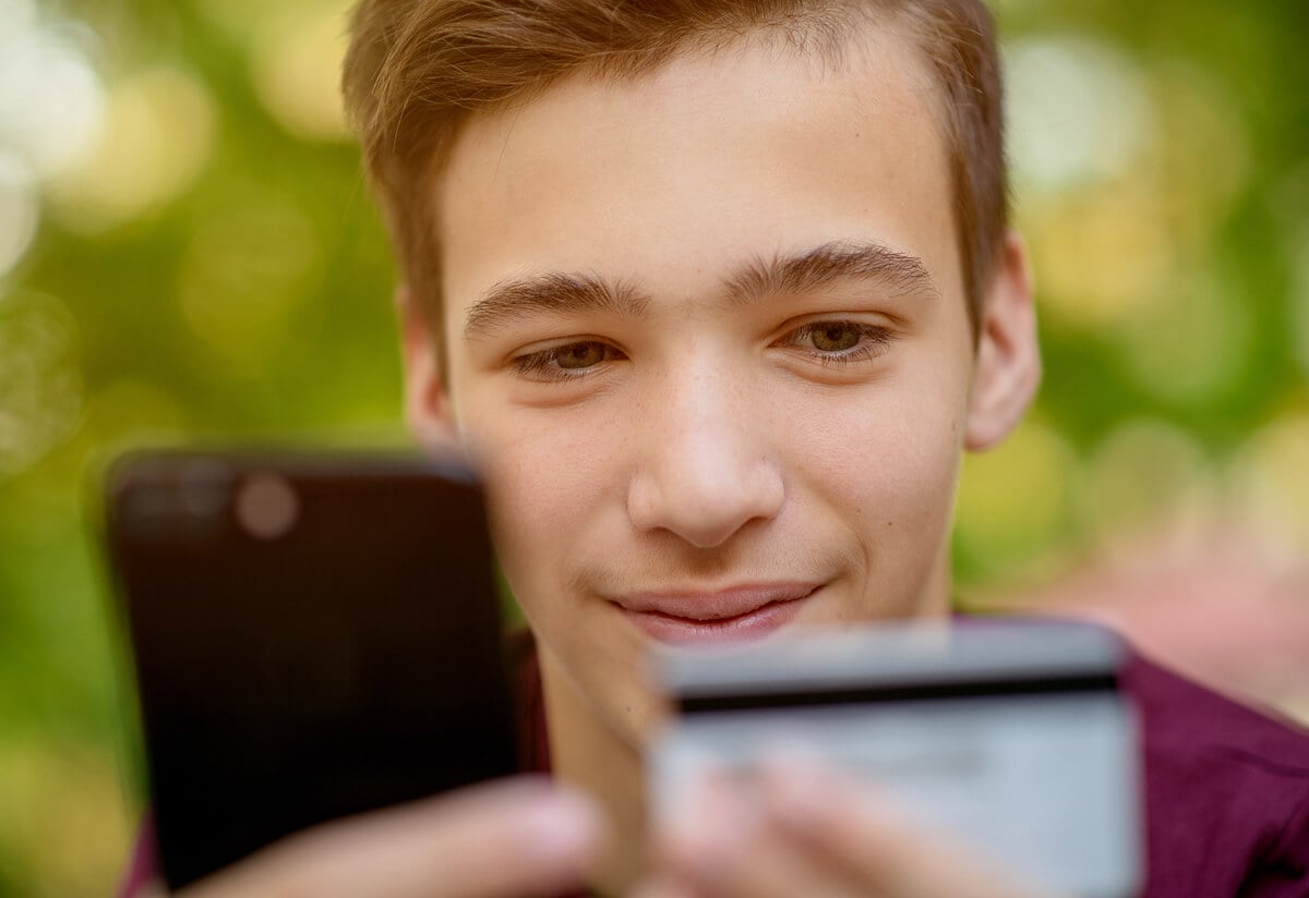 Teenage boy entering credit card number in smartphone