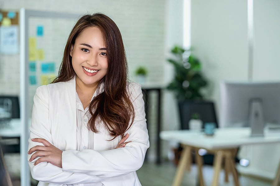 A young Asian female entrepreneur stands at the doorway to her new office