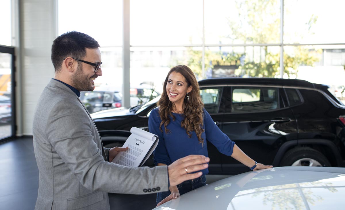 car salesman and woman looking at car