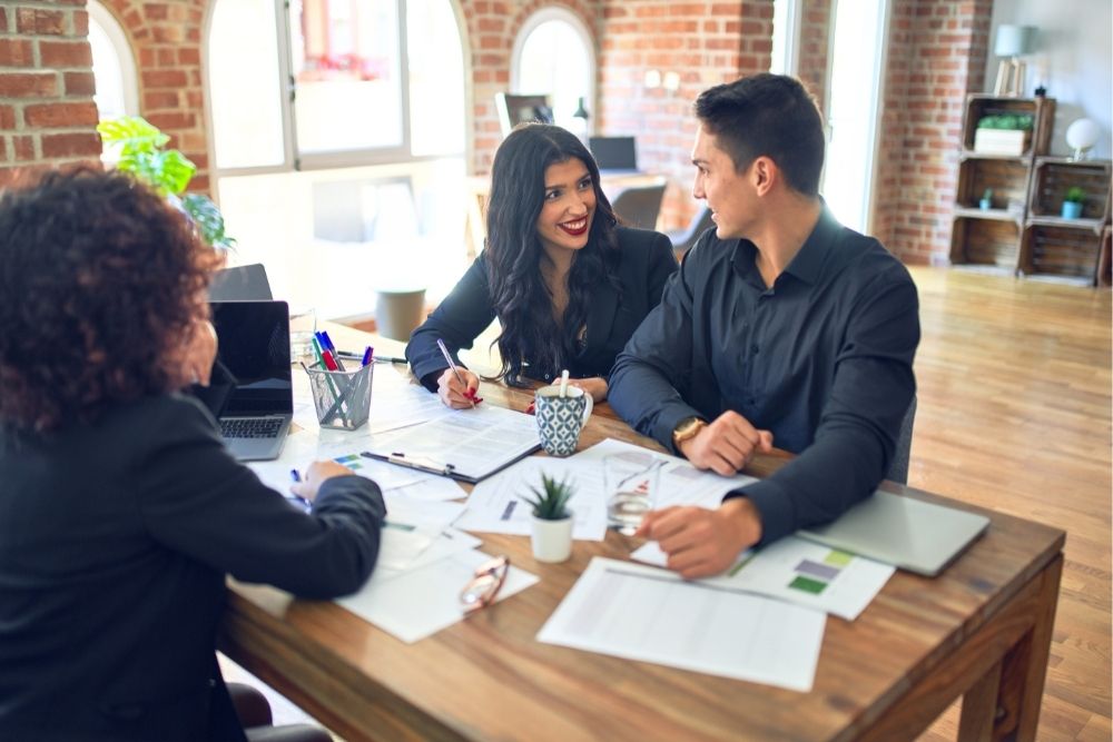 A young couple discusses mortgage pre-approval vs. pre-qualification in a lender's office.