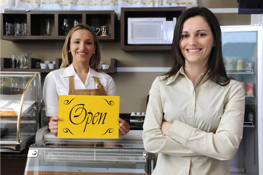 Small business owners smile as they open their cafe after securing an SBA loan