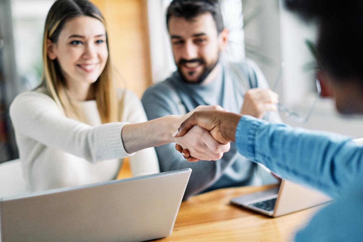 two people shaking hands over desk